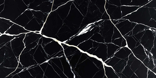 The image is a close-up of a black marble surface with white veins running through it. The veins appear to be irregularly shaped and vary in size and shape, creating a sense of depth and dimension. The black color of the marble is predominantly black, with some areas appearing lighter and darker, while others are lighter and more subtle. The texture of the surface is rough and uneven, with deep grooves and crevices. The overall effect is a striking contrast between the two colors.