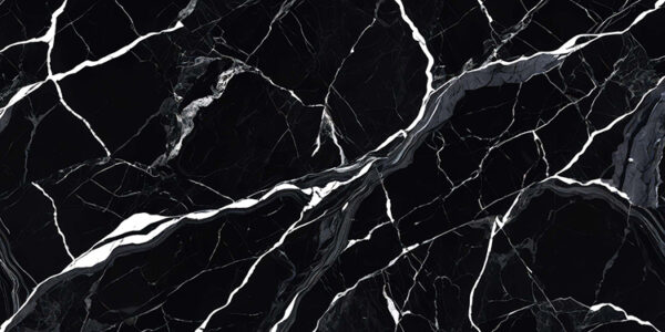 The image is a close-up of a black marble surface with white veins running through it. The veins appear to be irregularly shaped and vary in size and shape, creating a sense of depth and dimension. The black color of the marble is predominantly black, with some areas appearing lighter and darker, while others are lighter and more subtle. The texture of the surface is rough and uneven, with deep grooves and crevices. The overall effect is a striking contrast between the two colors.