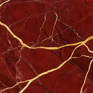 The image is a close-up of a marble surface with a deep red color. The surface has a rough texture with deep veins running through it, creating a pattern of lines and curves. The veins are gold in color and appear to be made of a shiny material. The overall effect is a luxurious and elegant design.