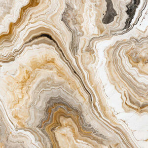 The image is a close-up of a marble surface. The marble has a unique pattern of swirls and curves, with different shades of beige, brown, and white. The colors blend together to create a beautiful and intricate design. The surface appears to be smooth and polished, with visible veins and grooves running through it. The overall effect is one of luxury and sophistication.