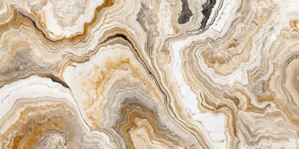 The image is a close-up of a marble surface. The marble has a unique pattern of swirls and curves, with different shades of beige, brown, and white. The colors blend together to create a beautiful and intricate design. The surface appears to be smooth and polished, with visible veins and grooves running through it. The overall effect is one of luxury and sophistication.