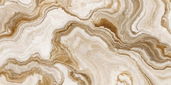 The image is a close-up of a marble surface. The marble has a unique pattern of swirls and curves, with different shades of beige, brown, and white. The colors blend together to create a beautiful and intricate design. The surface appears to be smooth and polished, with visible veins and grooves running through it. The overall effect is one of luxury and sophistication.