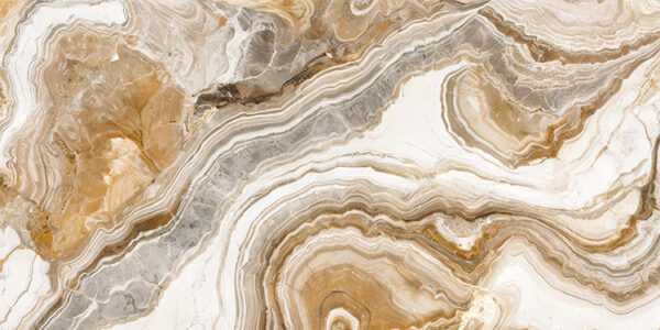 The image is a close-up of a marble surface. The marble has a unique pattern of swirls and curves, with different shades of beige, brown, and white. The colors blend together to create a beautiful and intricate design. The surface appears to be smooth and polished, with visible veins and grooves running through it. The overall effect is one of luxury and sophistication.